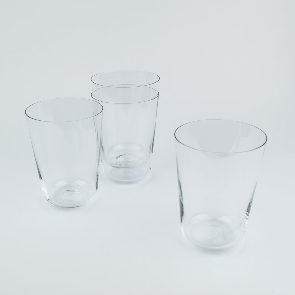 Four clear glass tumblers on a light gray background