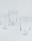 Four clear glass tumblers on a light gray background
