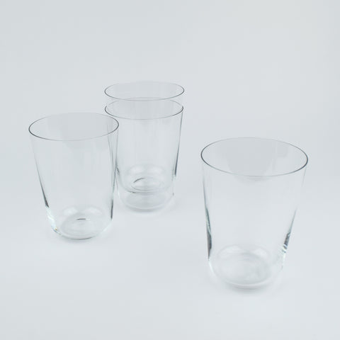 Four clear glass tumblers on a light gray background