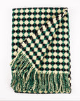 Green and white checkered blanket with fringes on a white background