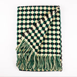 Green and white checkered blanket with fringes on a white background