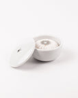 White ceramic bowl with lid and shaving soap on a white background