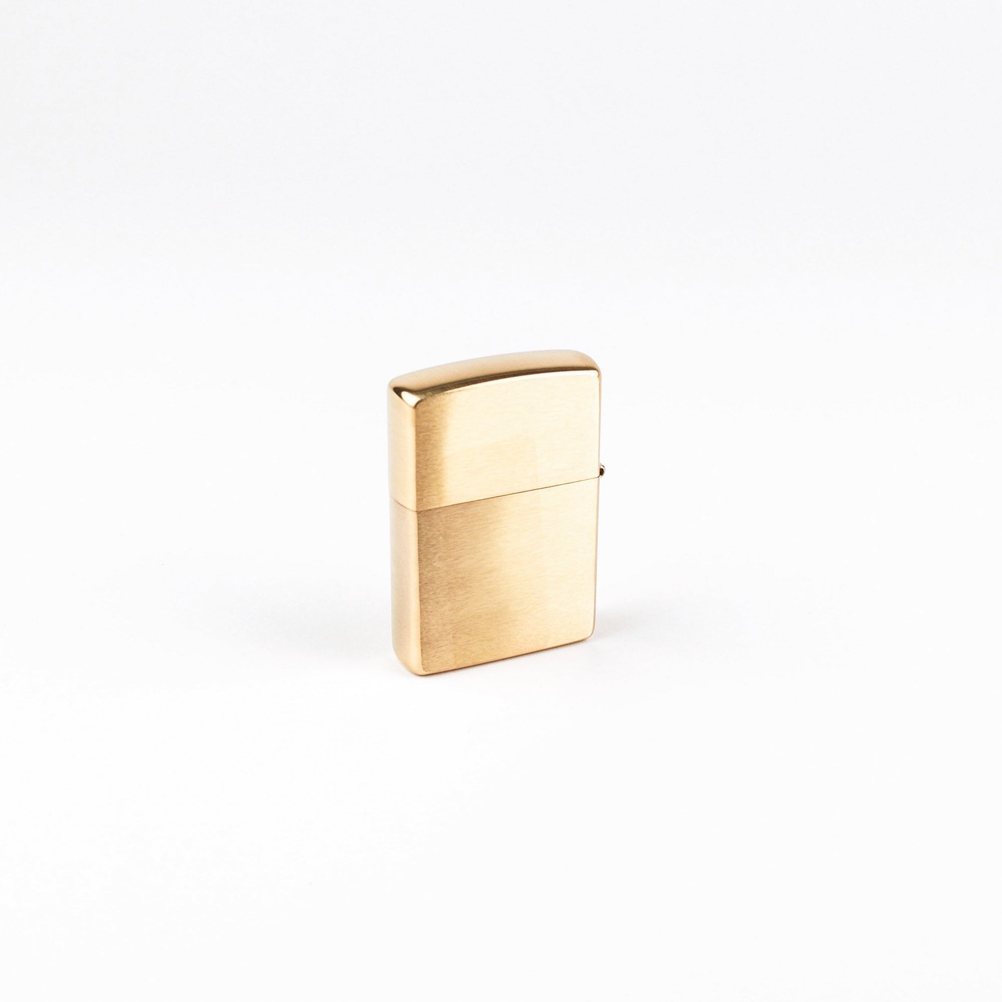 A classic rectangular lighter with a brushed gold finish, standing upright on a seamless white background.
