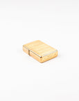 A small rectangular gold-toned metal lighter with a brushed finish and engraved markings, photographed on a clean white background.