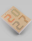 A notebook with a kraft paper cover featuring colorful geometric patterns, photographed at an angle on a neutral gray background.