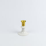 Decorative candle holder with gold top and white base on a light gray background