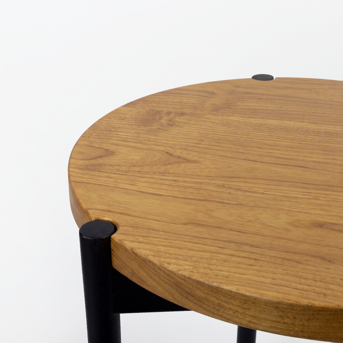 Close-up of a round wooden table top with a warm medium-brown wood grain finish and black metal legs, shown against a plain white background.