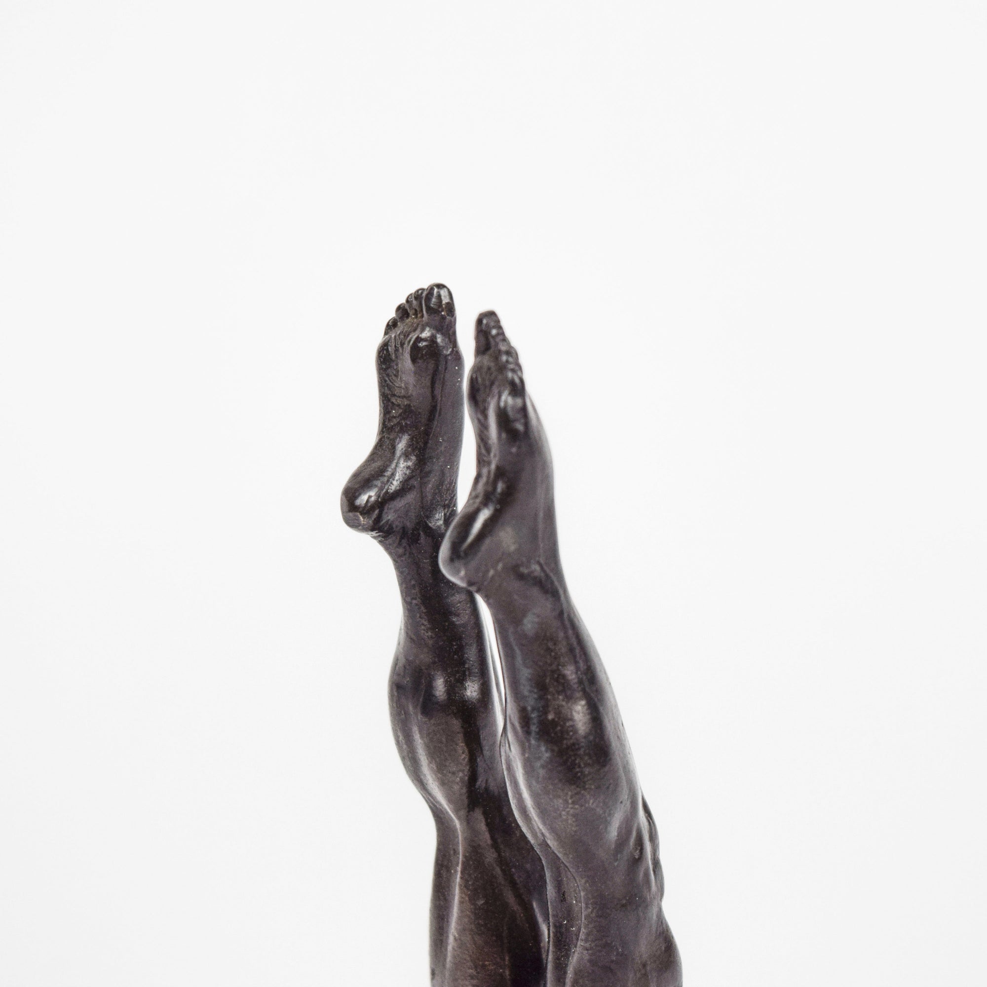 Detail of bronze sculpture of legs and feet on a white background