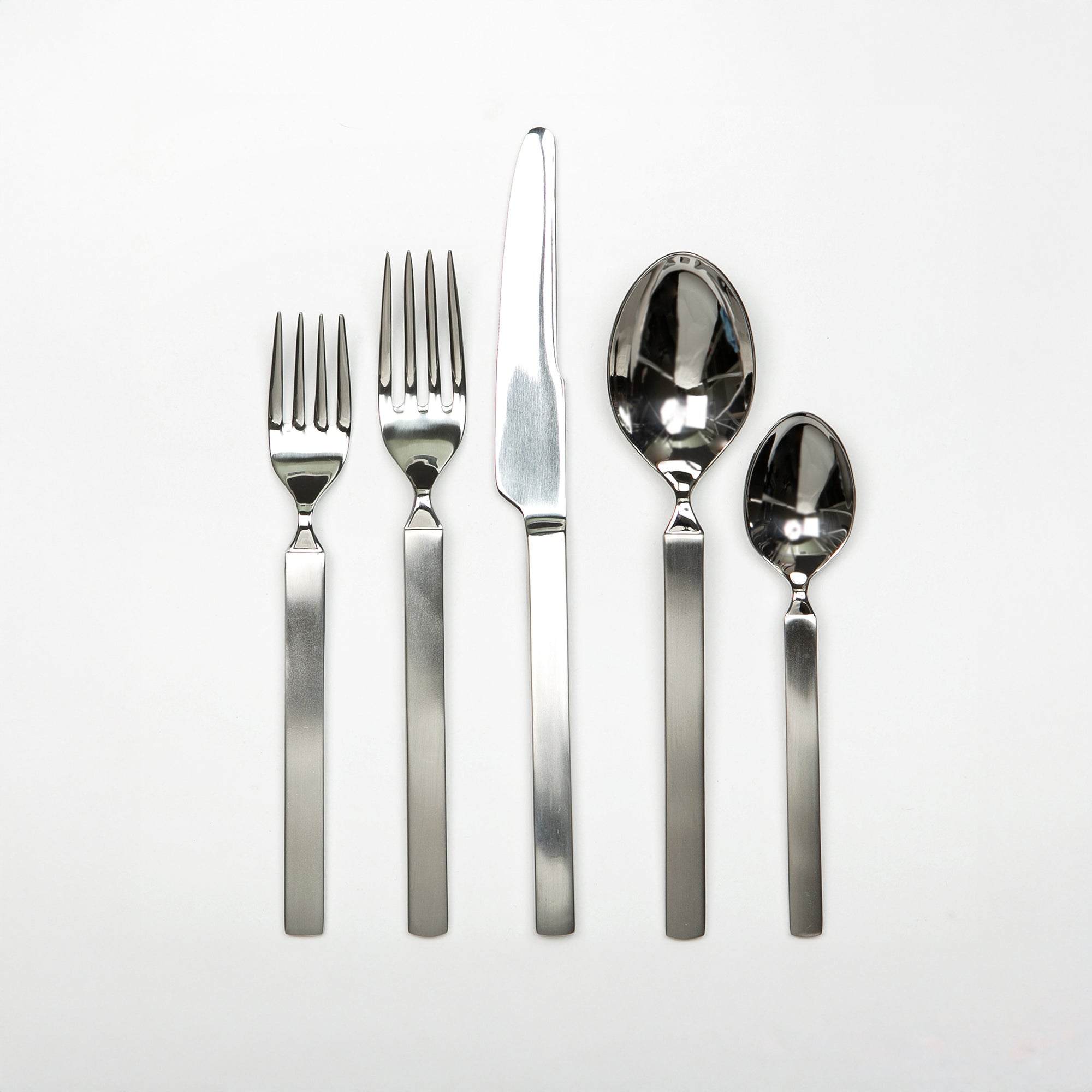 Set of silver cutlery including forks and knives on a white background