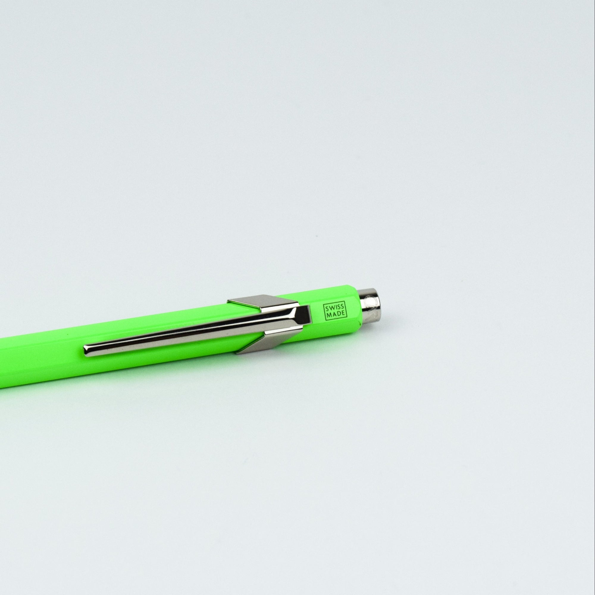 Neon green pen with silver clip on a light gray background