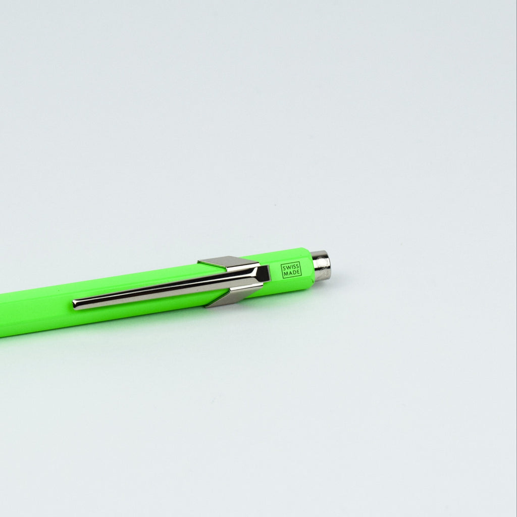 Neon green pen with silver clip on a light gray background