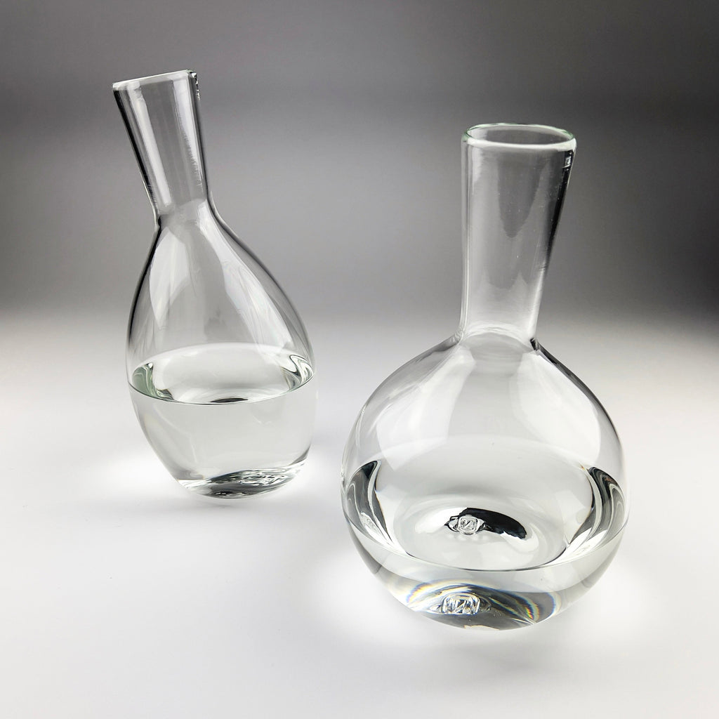 Two clear glass decanters on a gray background