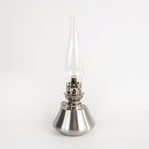 Metallic oil lamp with clear glass chimney on a white background
