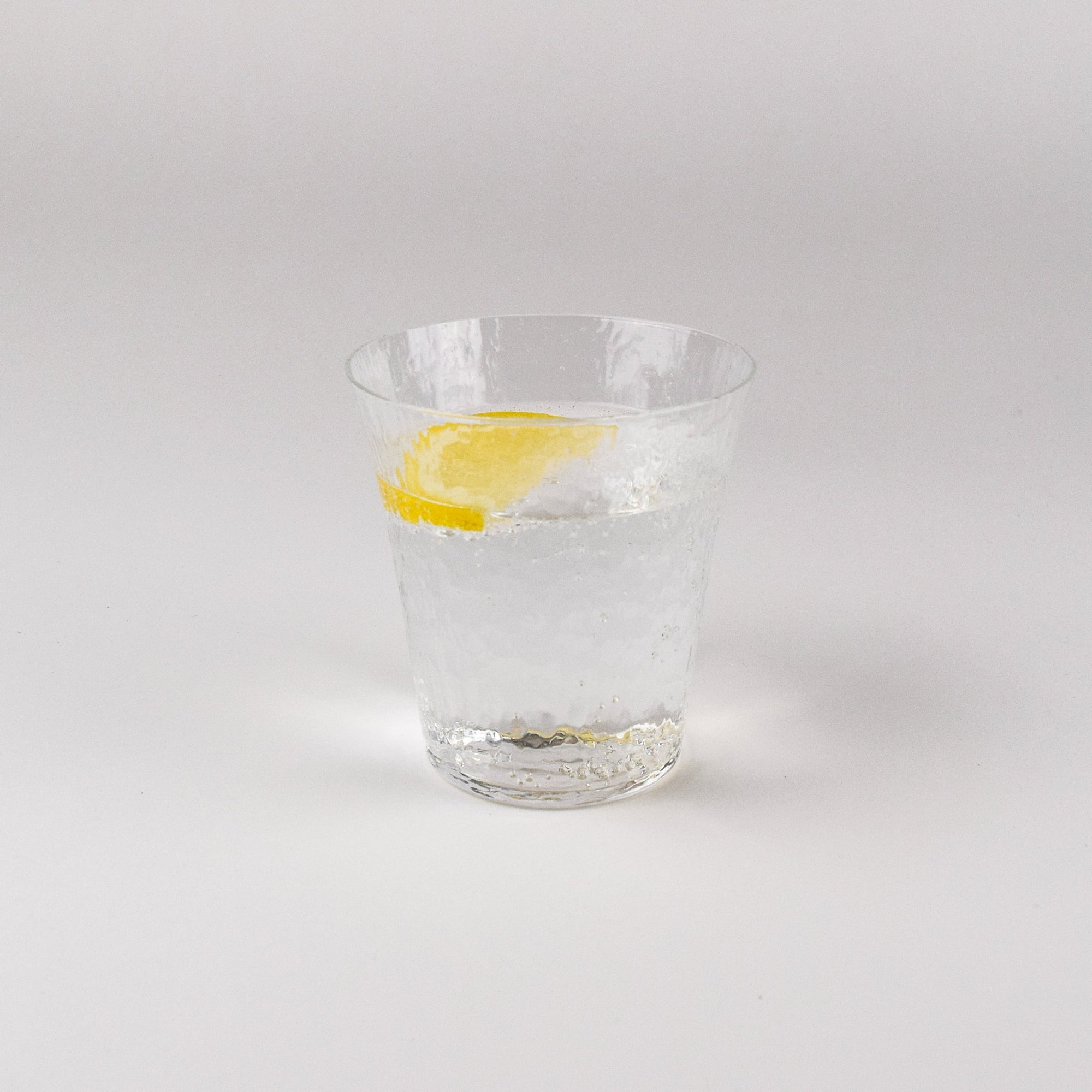 Clear glass with a lemon slice on a white background