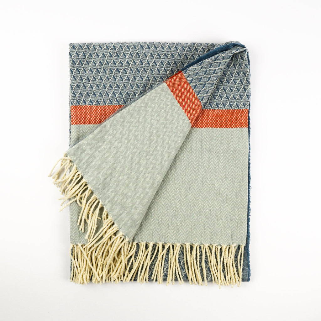 Textured blanket with geometric pattern and fringes on a white background