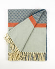 Textured blanket with geometric pattern and fringes on a white background