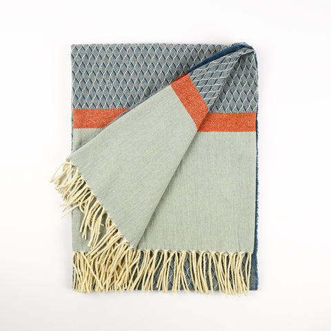 Textured blanket with geometric pattern and fringes on a white background