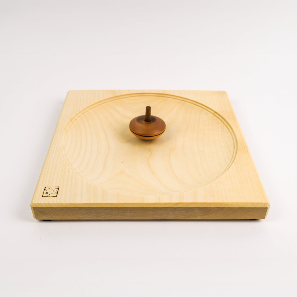Wooden spinning top on wooden spinning plate against a white background