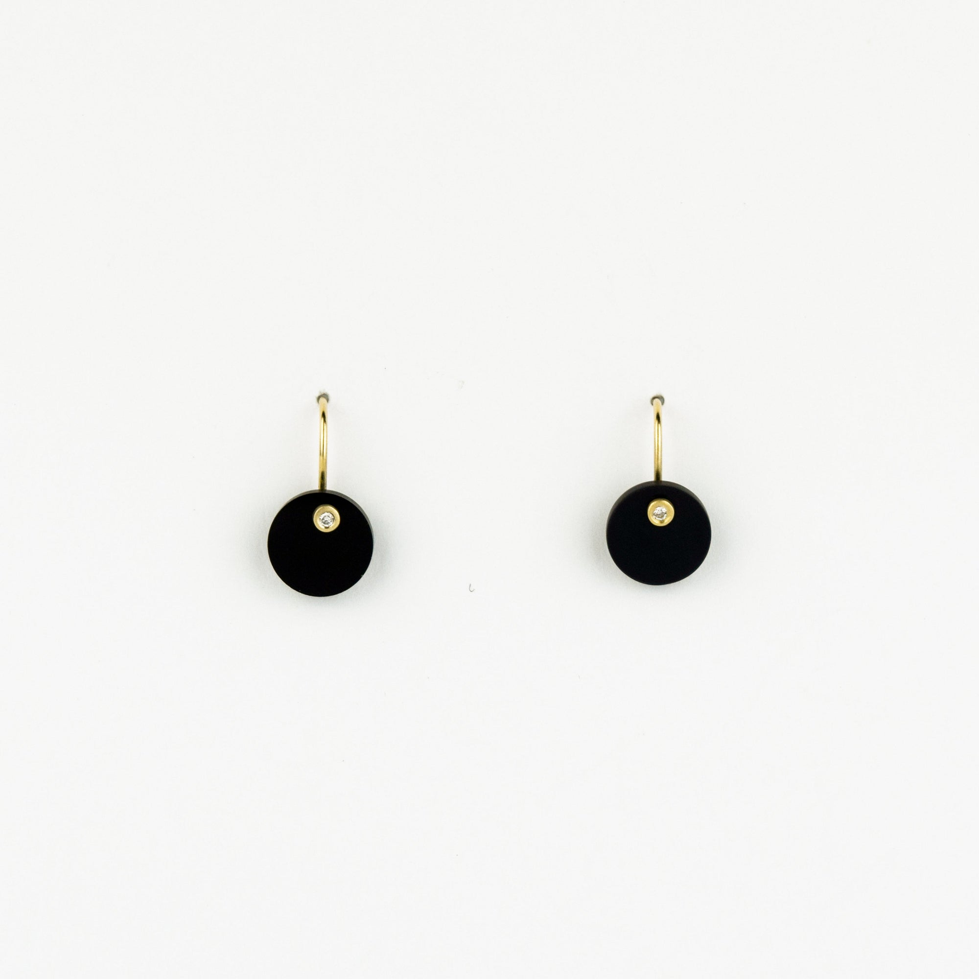 Pair of black earrings with gold hooks on a white background