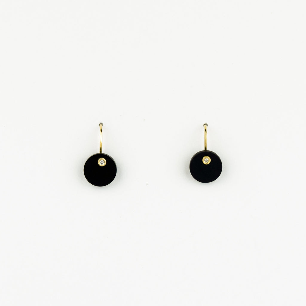 Pair of black earrings with gold hooks on a white background