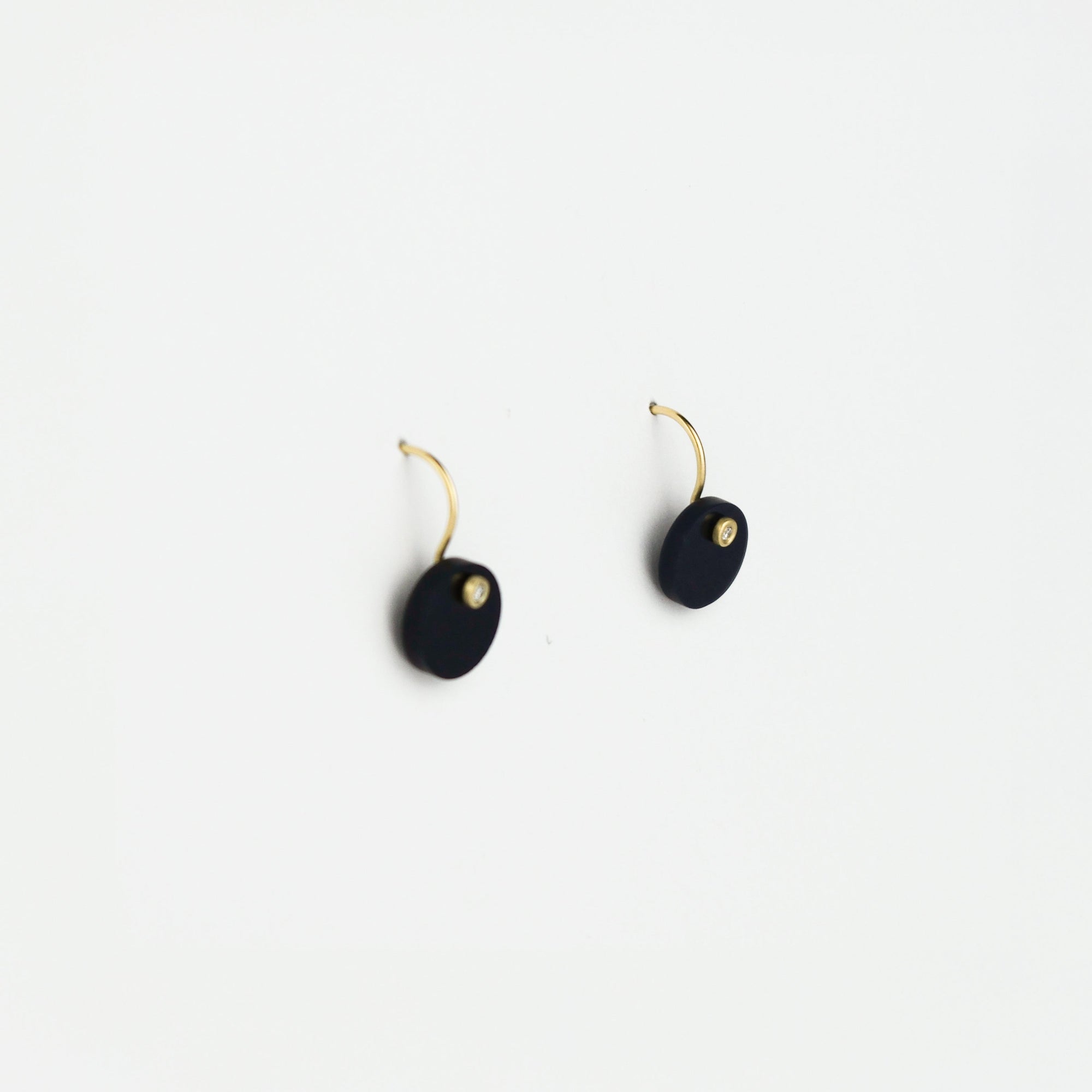 Pair of black earrings with gold accents on a white background