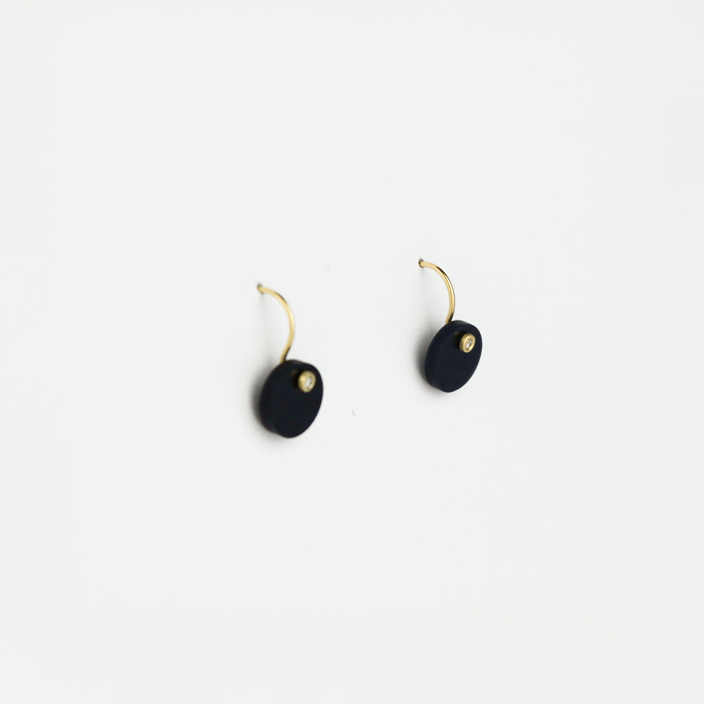 Pair of black earrings with gold accents on a white background