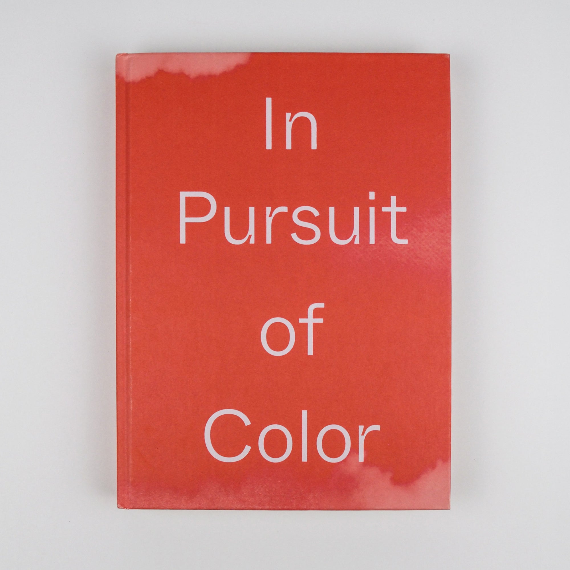 Book titled 'In Pursuit of Color' with red cover and white text on a light gray background