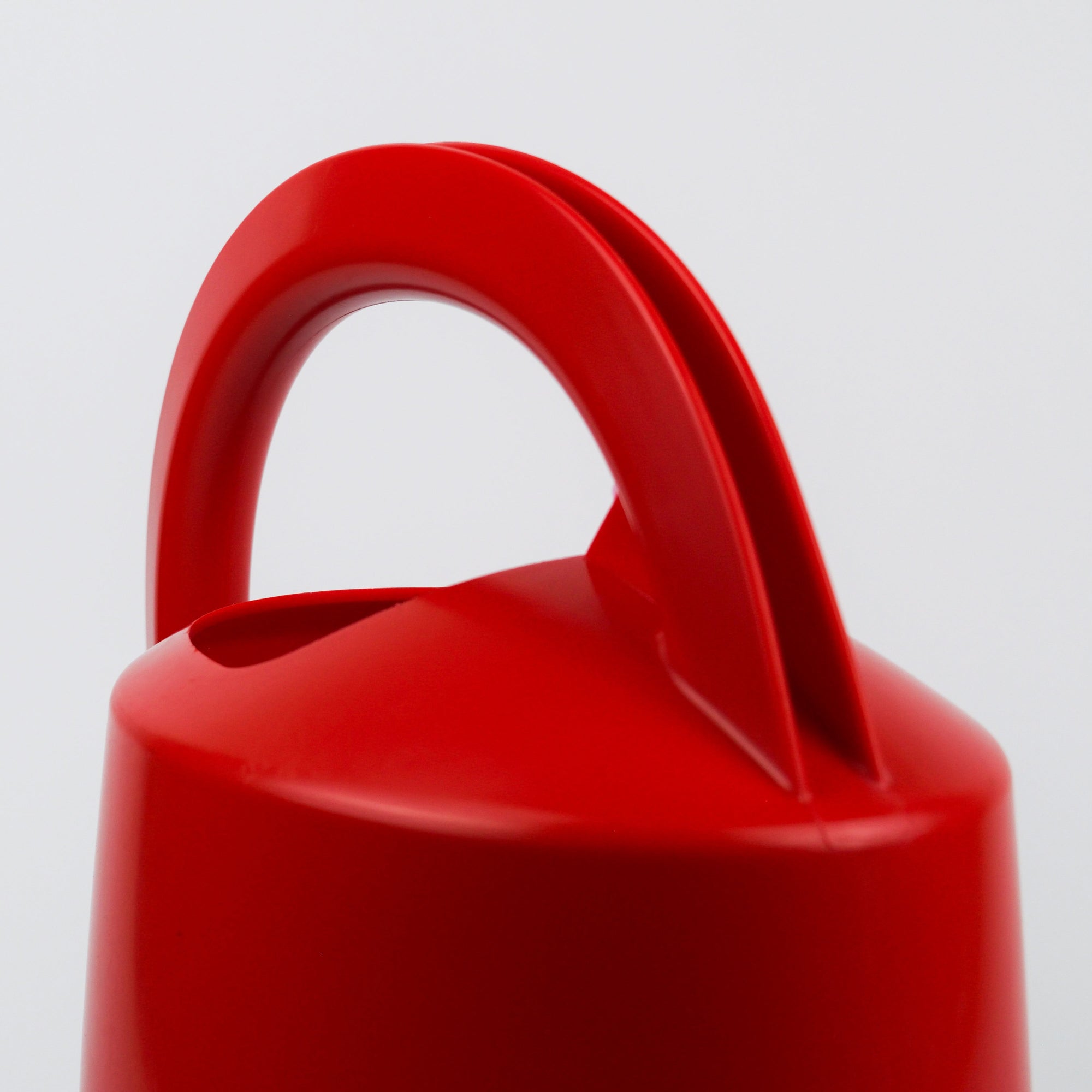 Close-up of a red plastic container with a handle on a light gray background