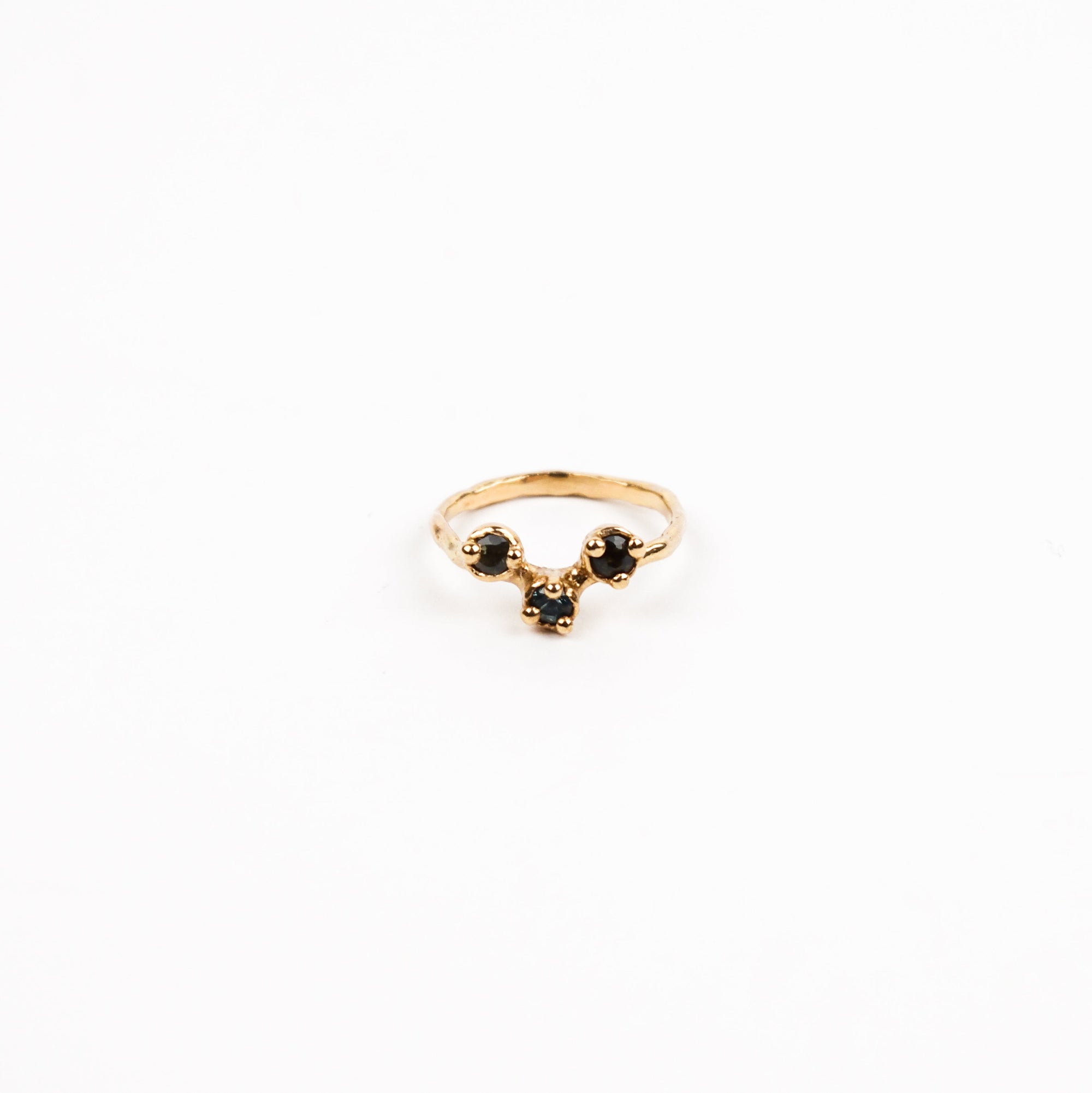 Gold ring with dark blue gemstones on a white background