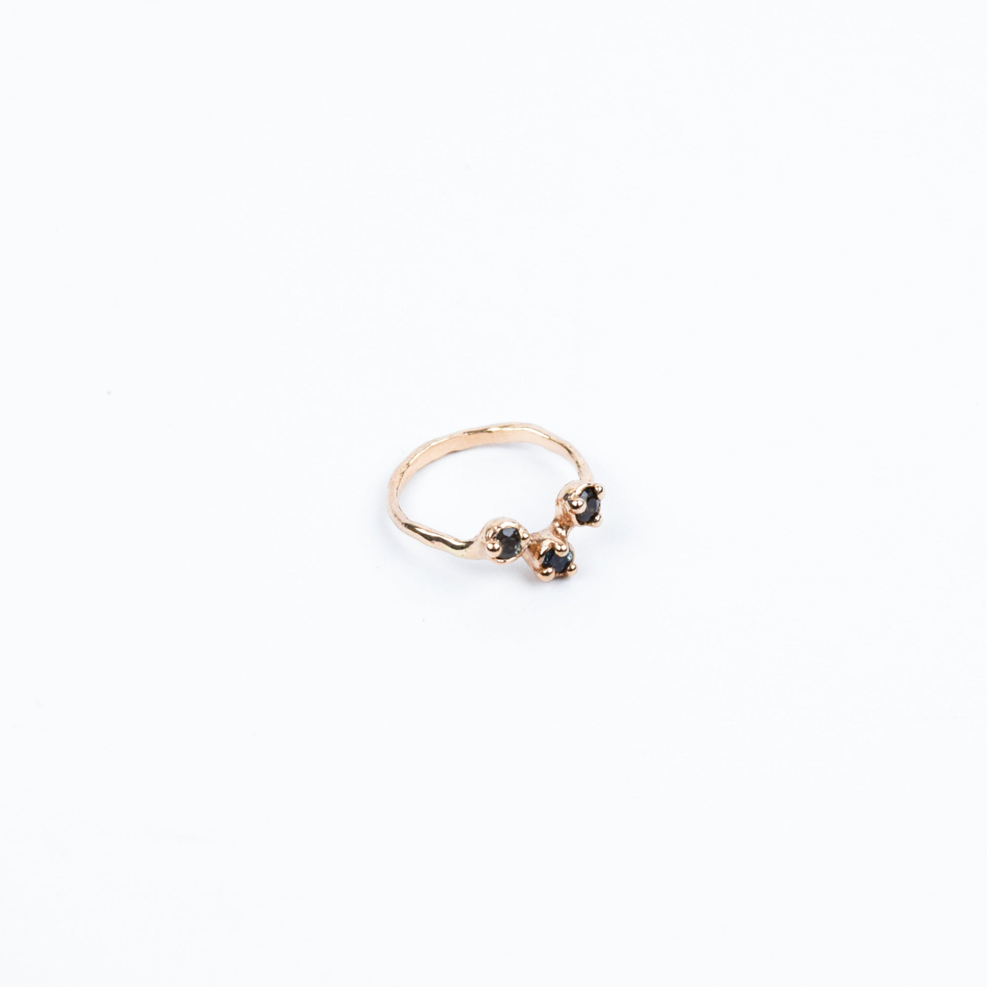 Gold ring with dark blue gemstones on a white background