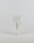 A clear glass double-walled cup with a small central gold-toned accent, photographed against a seamless light gray studio background.