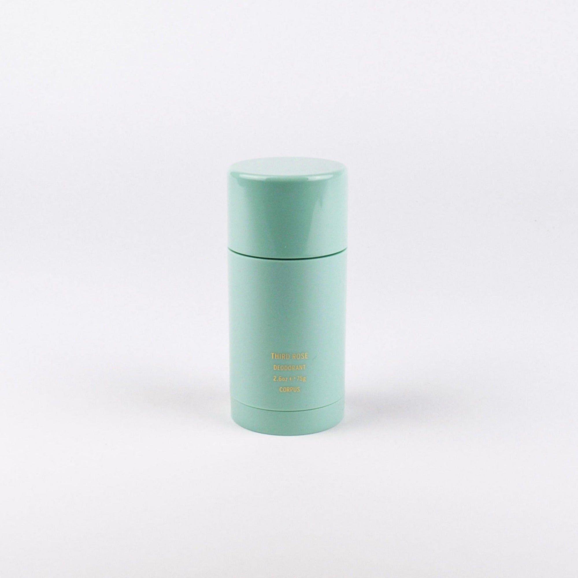 A mint green cylindrical cosmetic container with a matching lid, featuring small gold text on the front, set against a seamless white background.