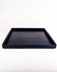 A square indigo blue wooden tray with a smooth, slightly glossy finish, photographed from a direct overhead angle on a seamless white background.
