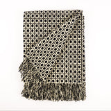 Patterned throw blanket with fringe on a white background