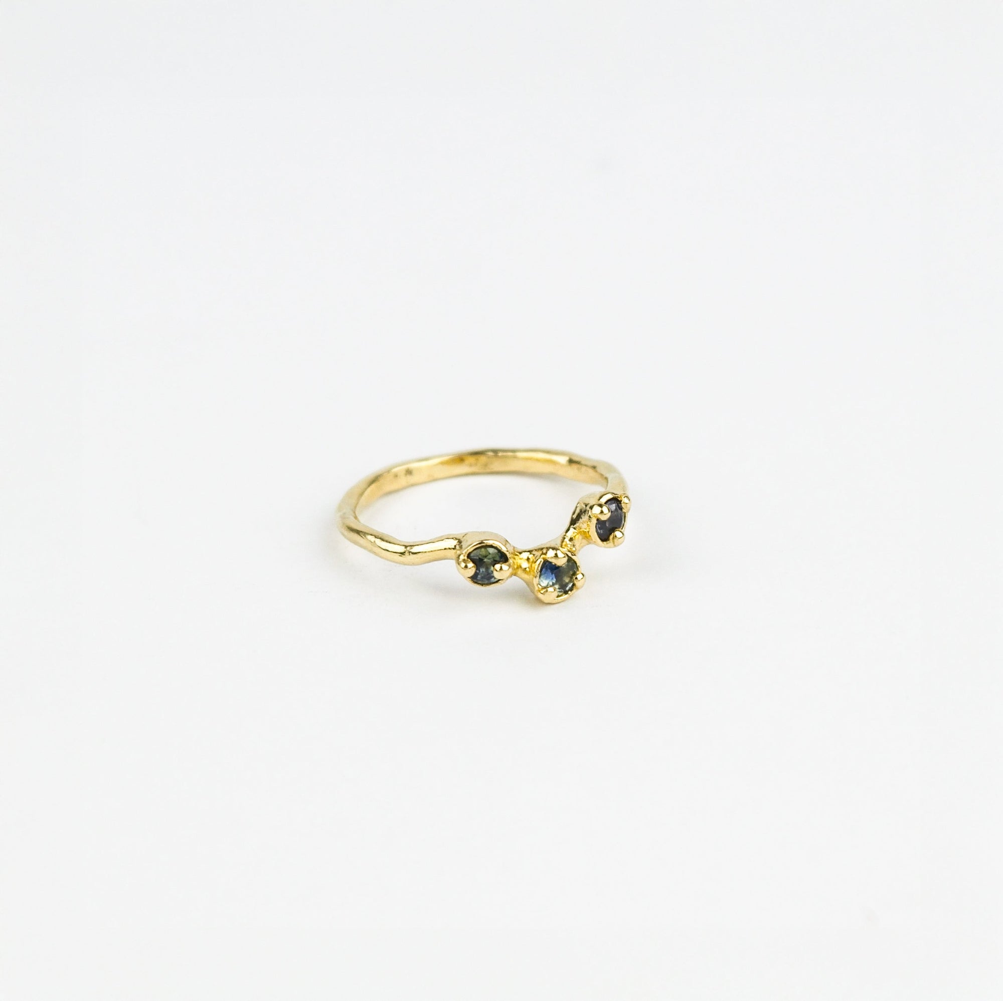 Gold ring with three blue gemstones on a white background