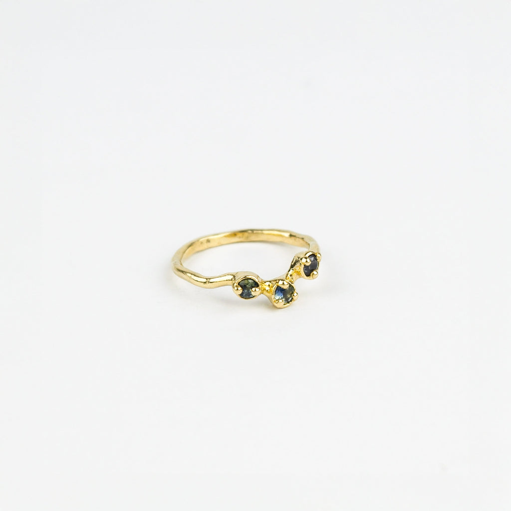 Gold ring with three blue gemstones on a white background