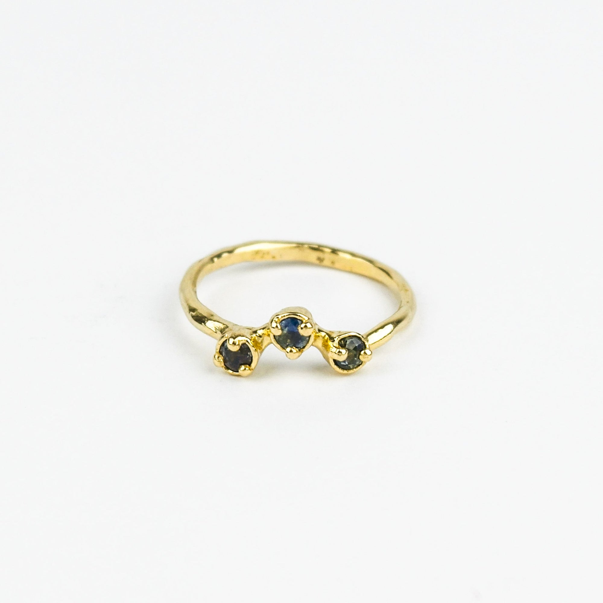 Gold ring with three embedded stones on a white background