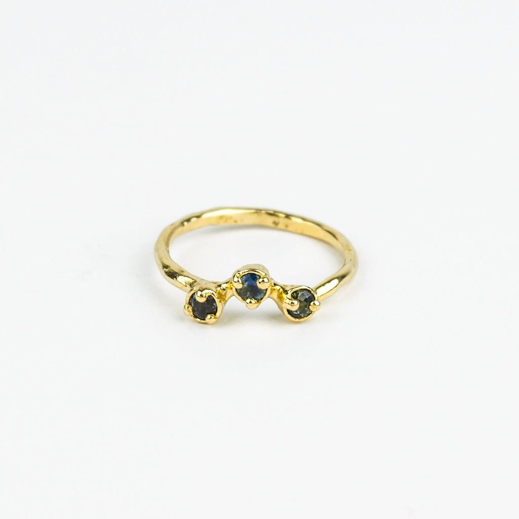 Gold ring with three embedded stones on a white background
