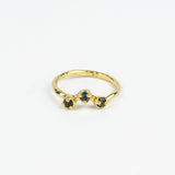 Gold ring with three embedded stones on a white background
