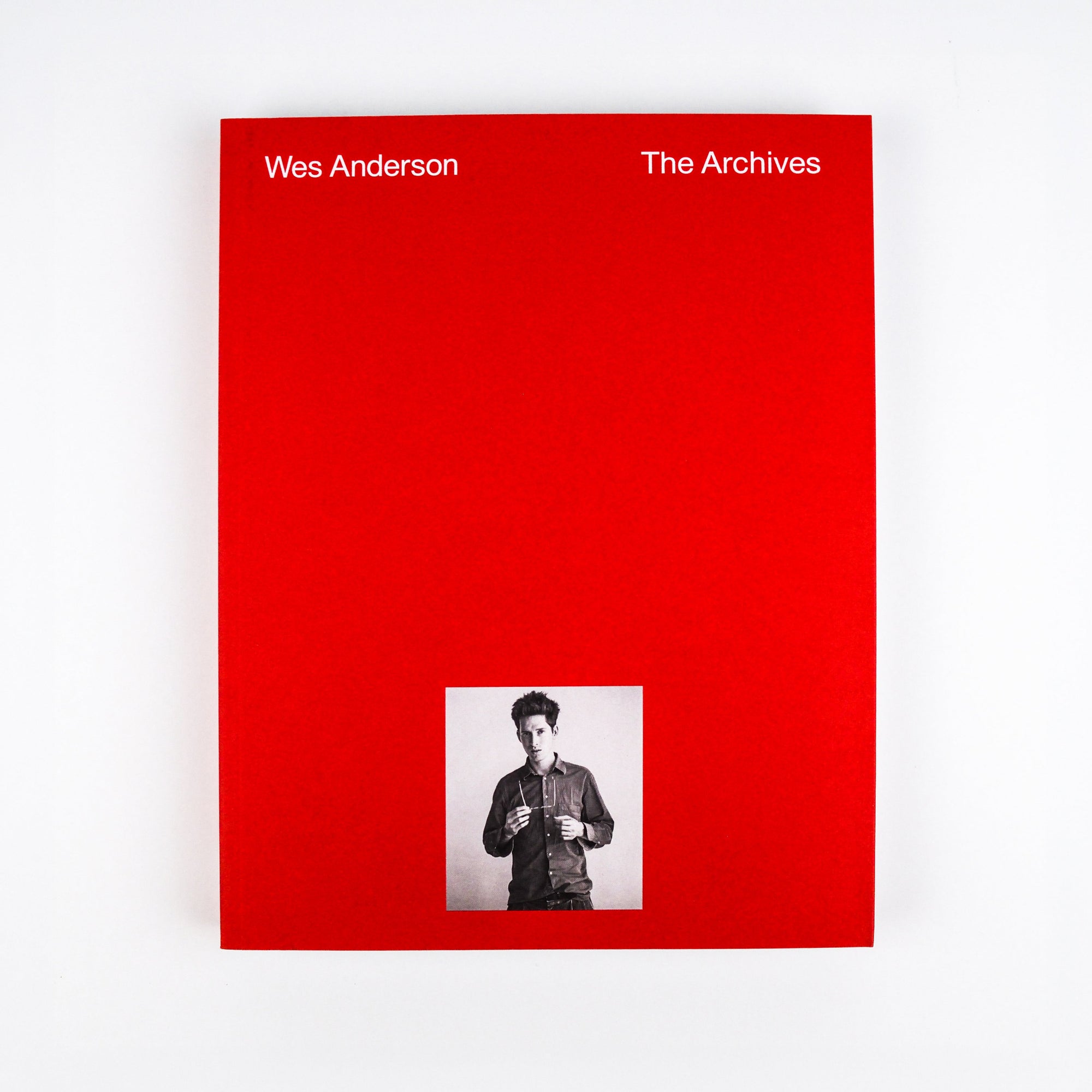 Book cover of 'Wes Anderson The Archives' with a red background and a small inset photo of a person.