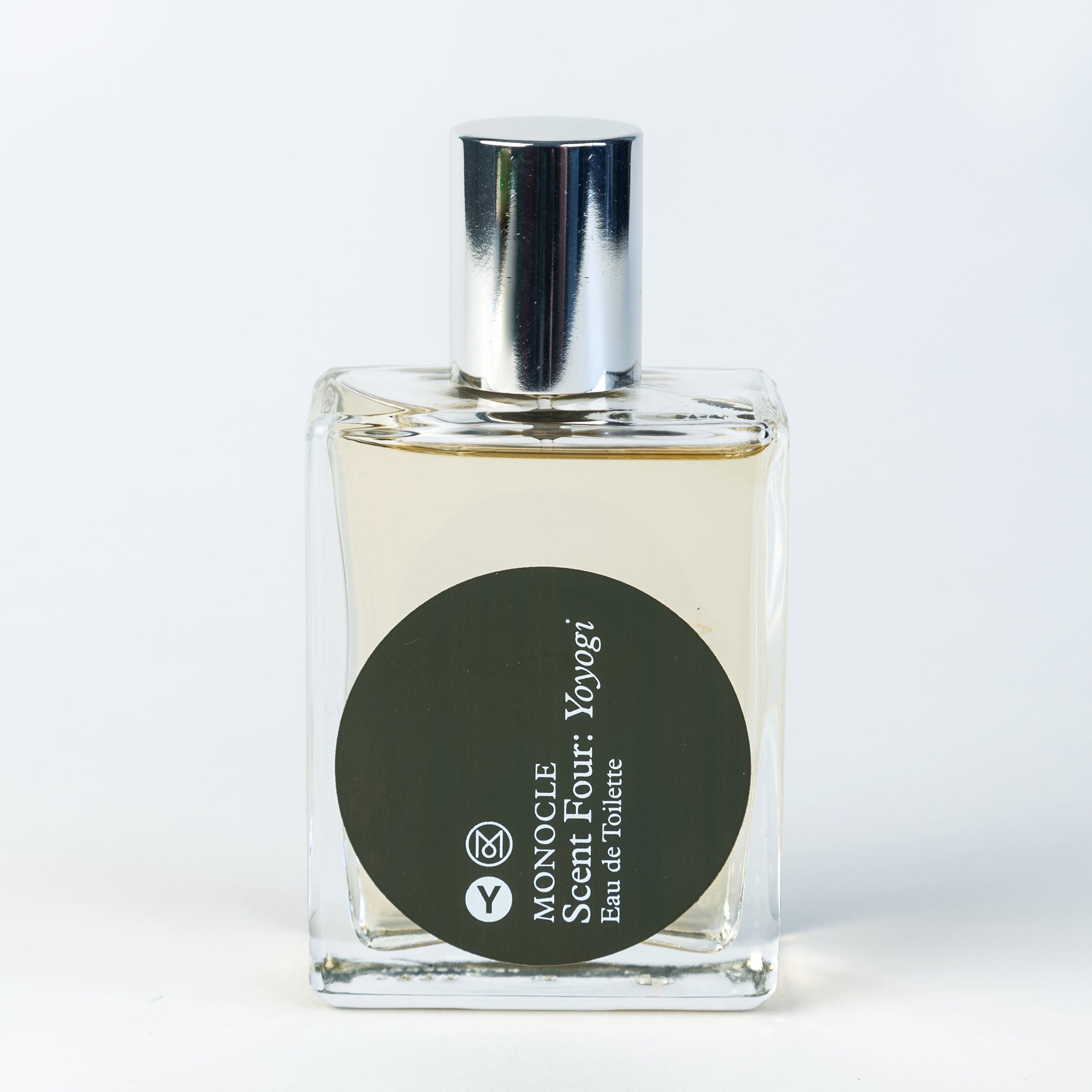 A clear glass bottle of Comme des Garçons x Monocle Parfums fragrance with a silver cap and a black label featuring white text. The label reads '04 Yoyogi' and 'Eau de Toilette'.