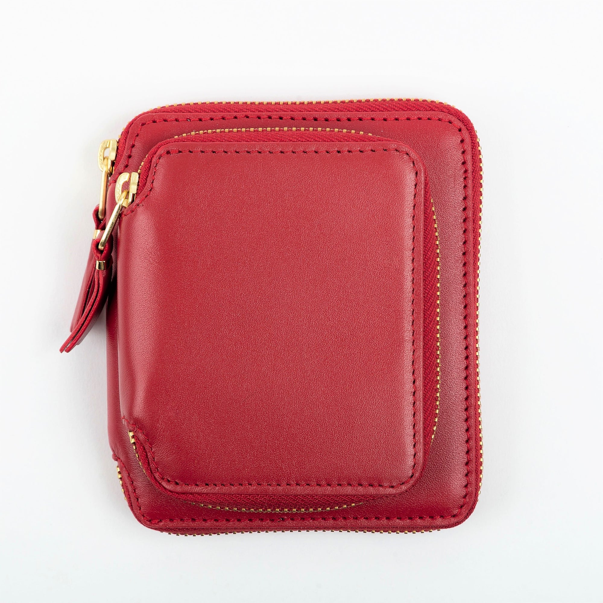 A red leather wallet with gold toned metal hardware and a zipper around the exterior pocket.